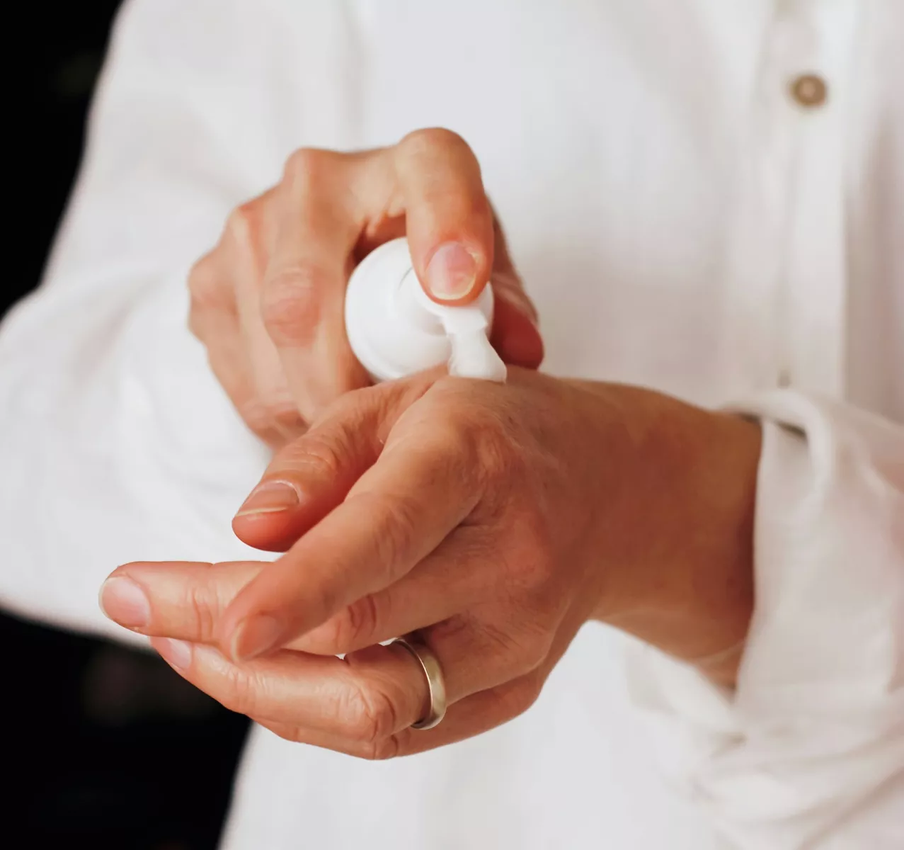 Mujer utilizando una crema en la mano