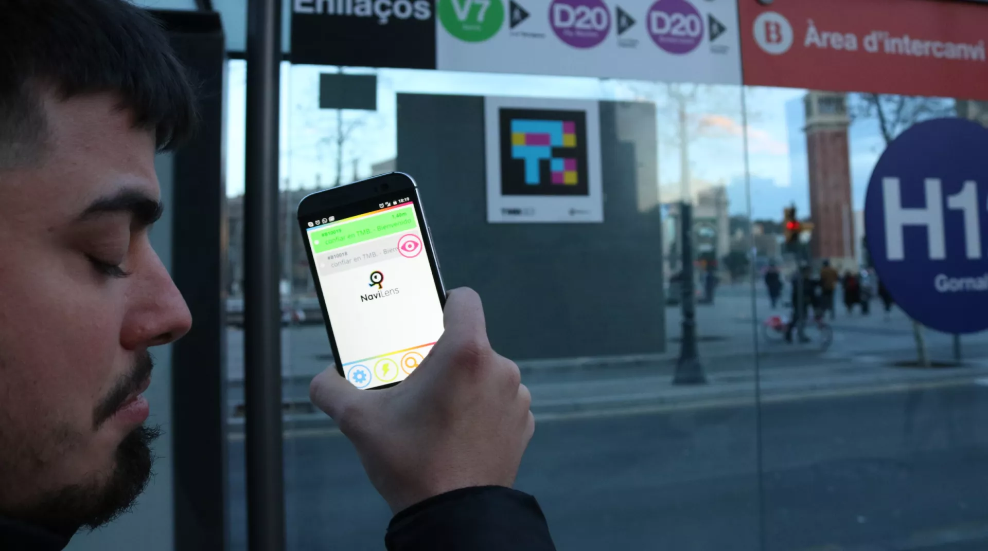 Persona escaneando un código accesible NaviLens en una parada de autobús